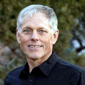 David Coblentz is a light-skinned male with grey hair, green eyes, and a warm smile. He wears a black shirt.
