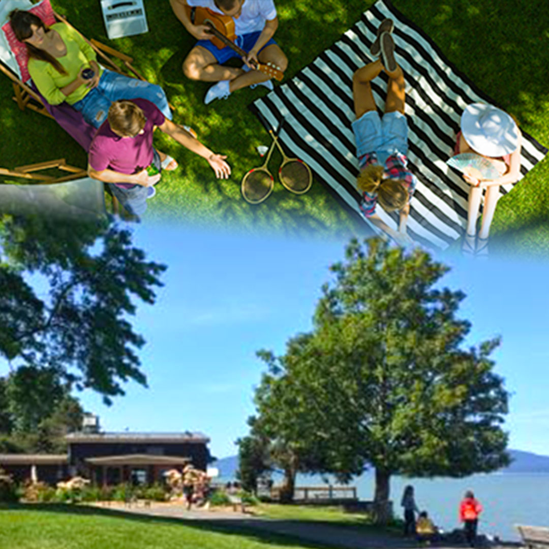People relaxing on striped picnic blanket on green lawn and people strolling by green trees at Boulevard Park in Bellingham.