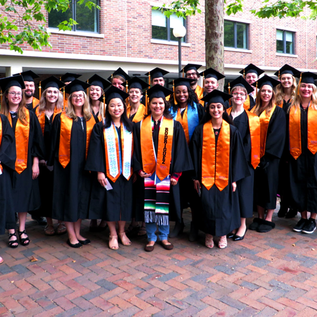 Large group of nursing graduates in their black robes, orange hoods, and mortar boards