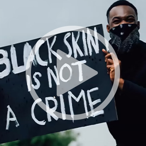 African American holding a sign that says "Black Skin is Not a Crime" with a video play button over it
