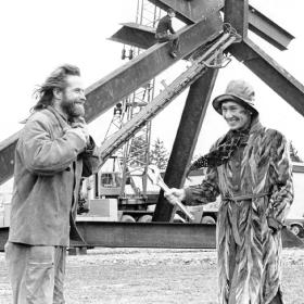 Virgina Wright smiles broadly and holds a wrench, standing next to Mark di Suvero in front of For Handel in this 1974 photo