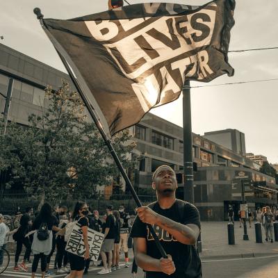 Black man waving a large Black Lives Matter flag