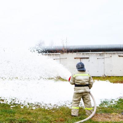 Firefighter spraying white chemical foam
