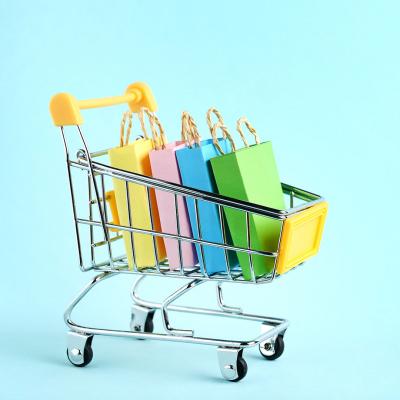 Miniature shopping cart filled with colorful gift bags