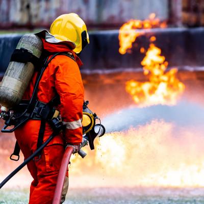 Firefighter spraying chemical foam on a large fire