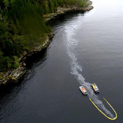 Aerial view of ocean waters with large oil spill stemming from shipping vessel
