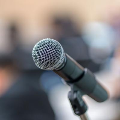 A microphone with a blurry background of people in a conference
