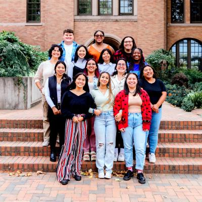A diverse group of WWU students in the education program gather in front of Miller Hall. They are all smiling and standing close to each other.