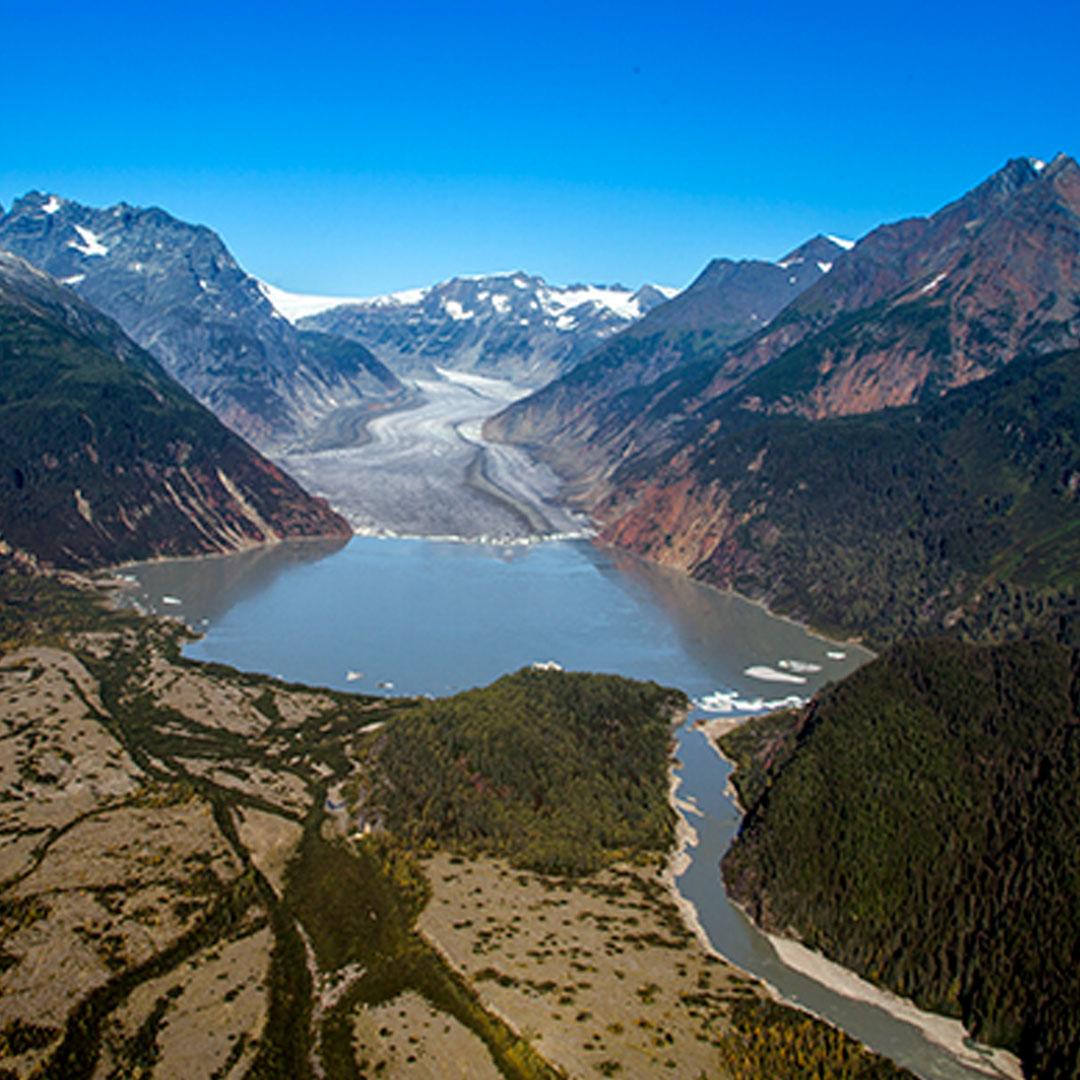 Surrounded by mountains, a large lake forms at the base of a melting glacier.