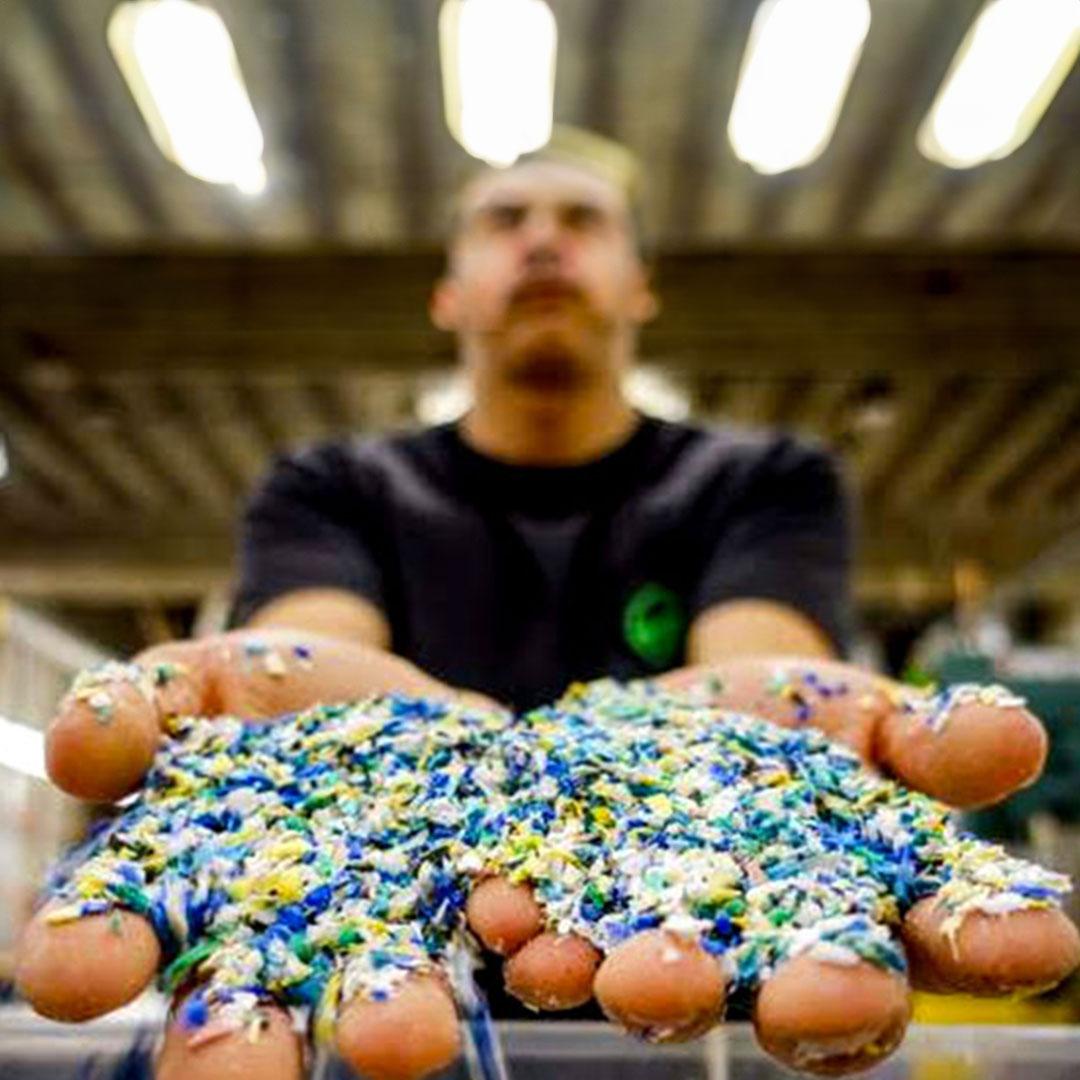 Close up of a man's outstretched hands holding colored plastic granules.