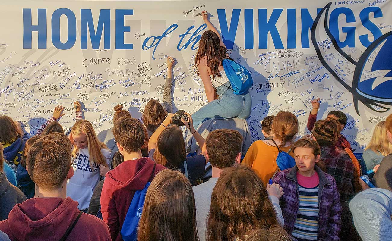 Students signing the "Home of the Vikings" banner during Paint B'ham Blue for Western Washington University